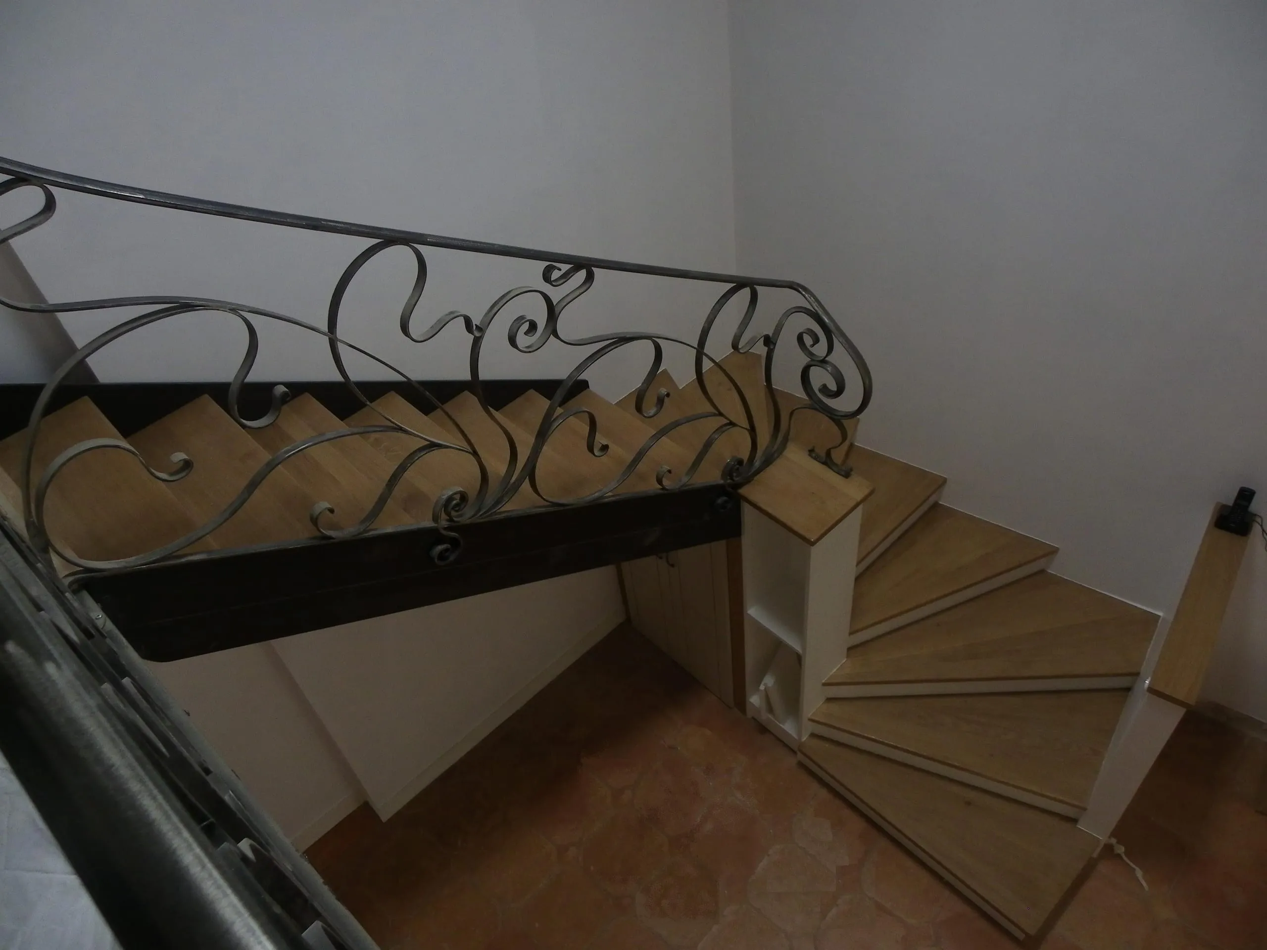 Escalier en bois avec garde-corps métallique à volutes décoratives