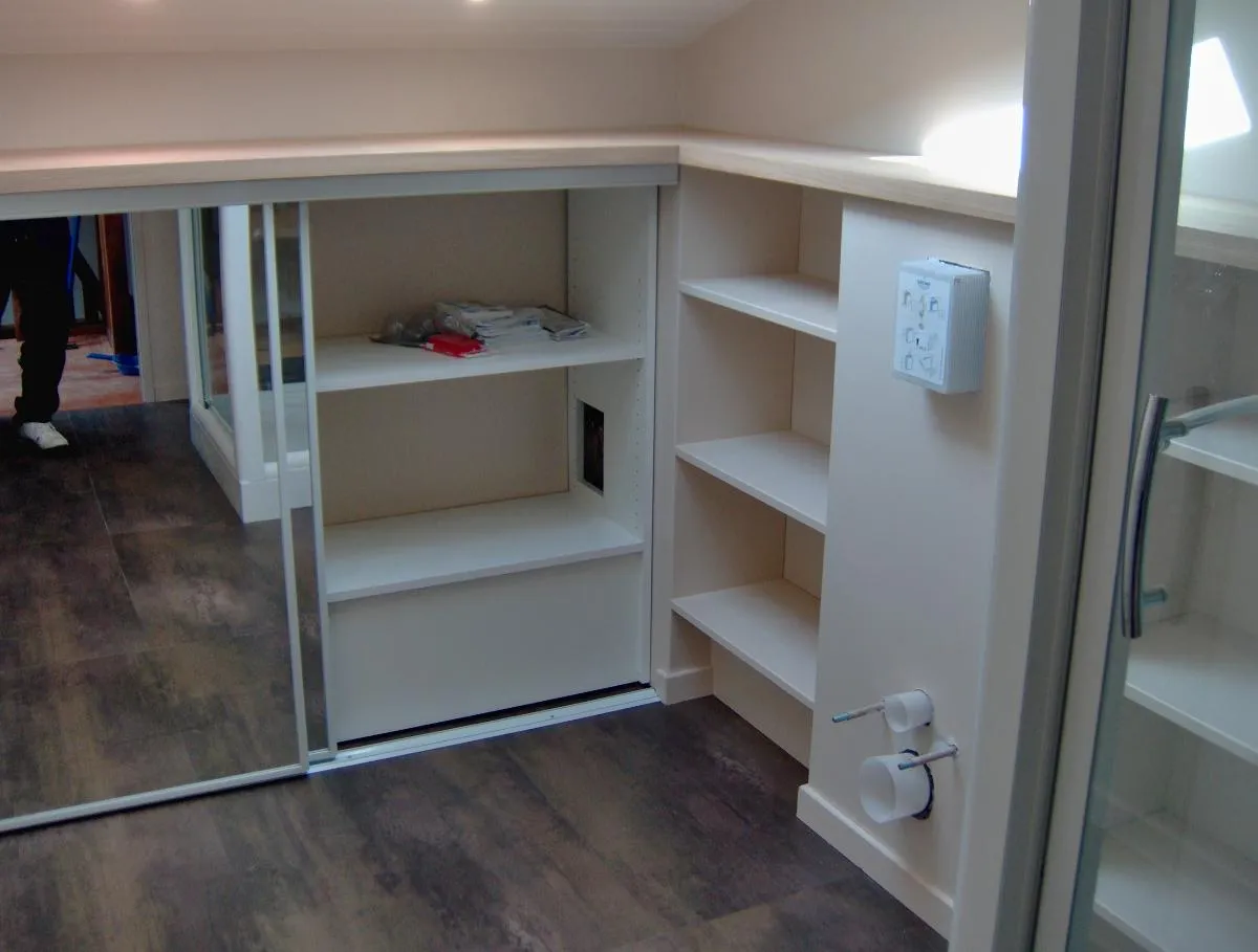 Rangements sous combles avec portes coulissantes en miroir et étagères latérales
