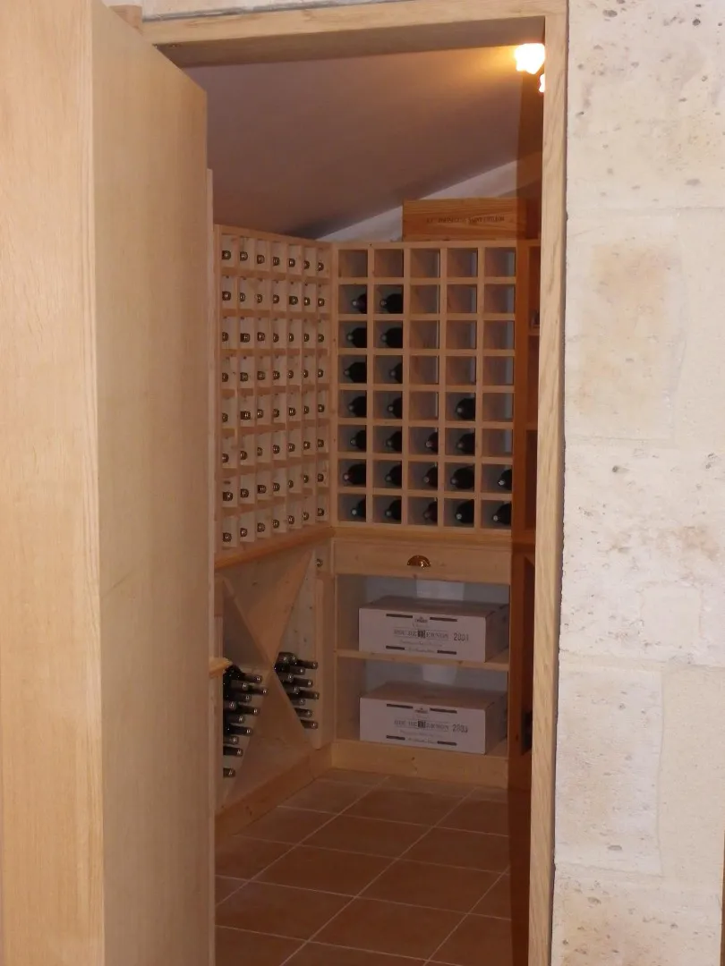 Cave à vin en bois visible derrière une porte ouverte