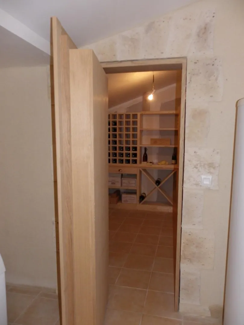 Porte en bois ouverte donnant accès aux casiers de la cave à vin